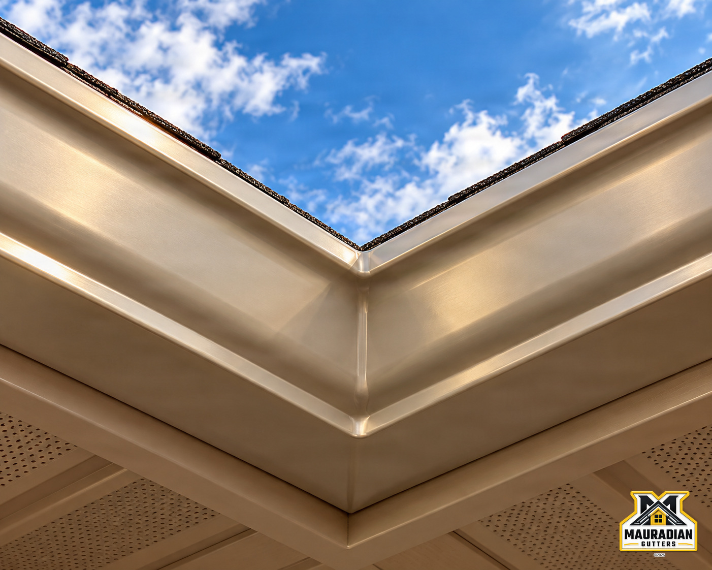 Close-up of a seamless aluminum gutter corner showing the finished corner and roofline against a blue sky.